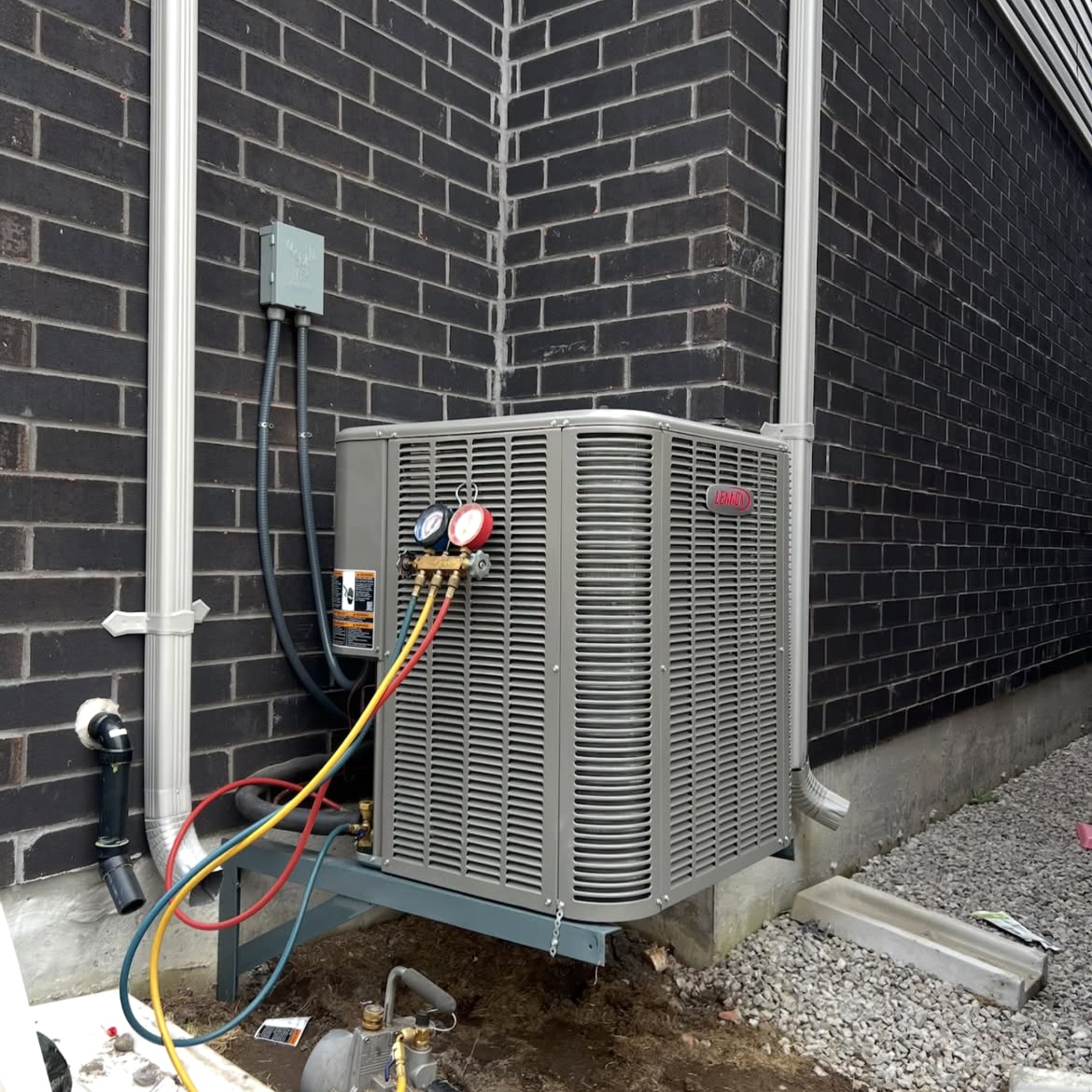 Air conditioning service gauges connected to outdoor equipment